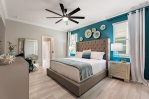 Un dormitorio con una cama grande, un ventilador de techo y una mesita de noche con lámpara.