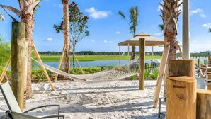 Une plage avec des hamacs, une structure en bois et une vue sur un lac.