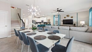 Un salon moderne comprenant un coin repas, un canapé, un téléviseur et un ventilateur de plafond.