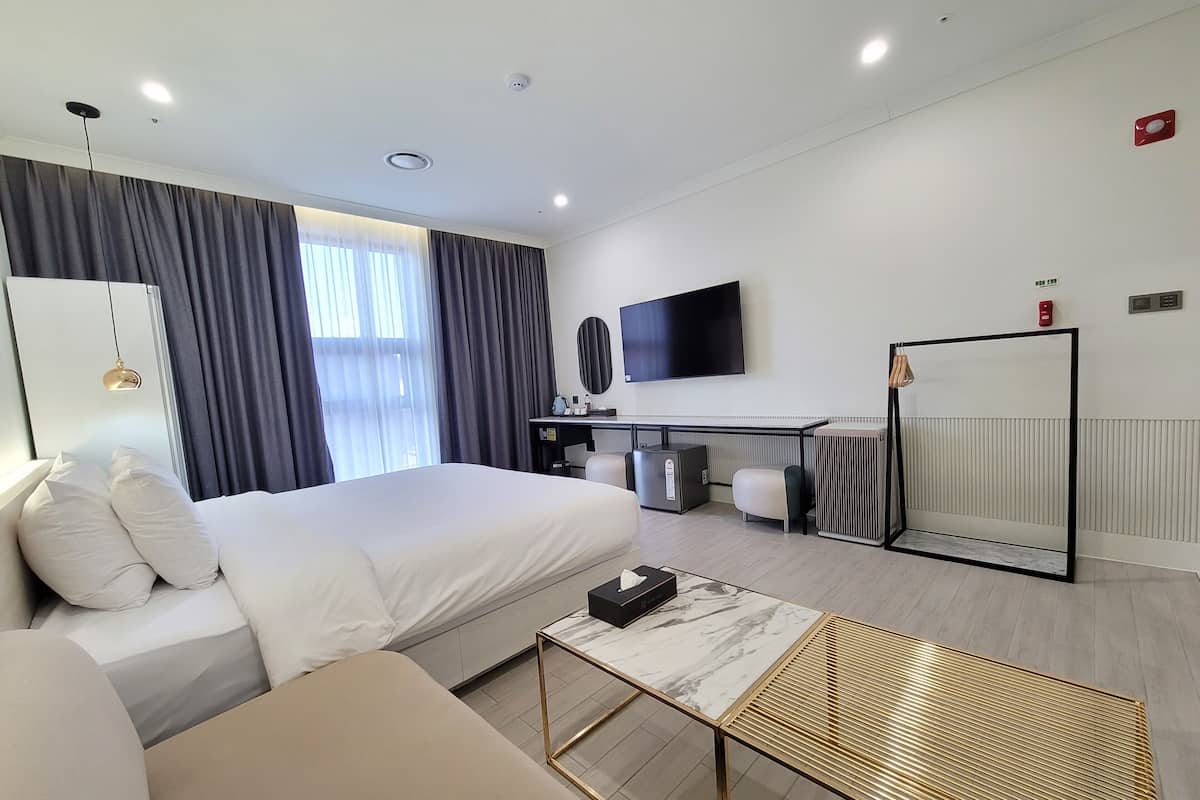 Una habitación de hotel moderna con cama, escritorio, televisor y radiador.