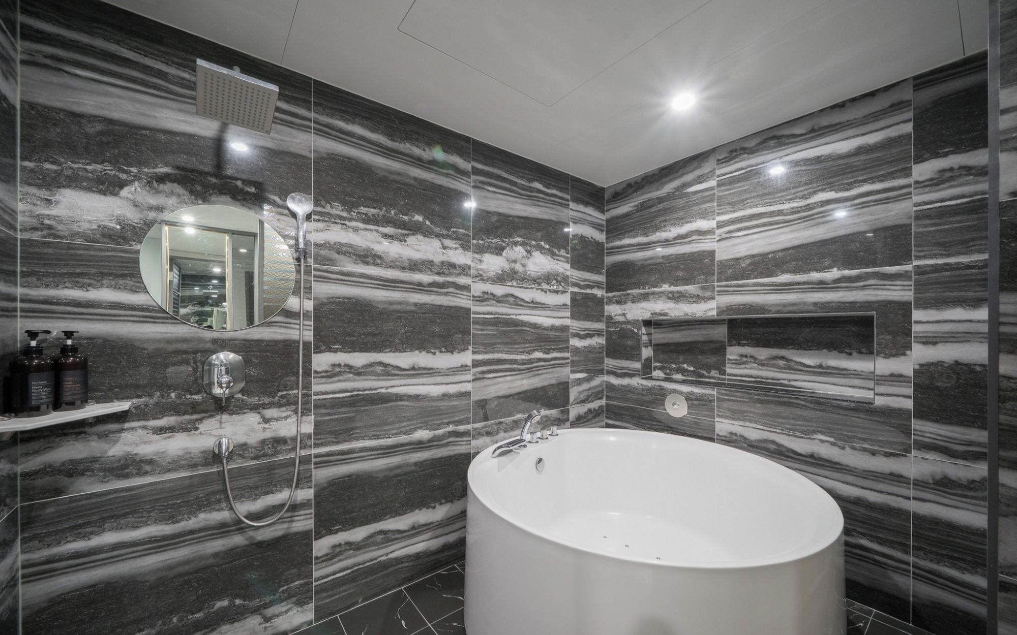 Un baño moderno con una bañera independiente, un espejo instalado en la pared y un cabezal de ducha.