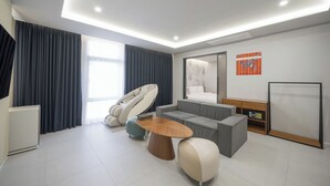 A modern hotel room with a massage chair, a sofa, a small table, and a bed. - Hotel PIED Suseong (Daegu)