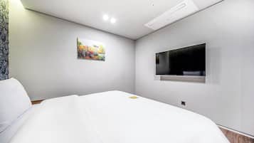 Una habitación de hotel moderna con una cama, un cuadro y un televisor fijado a la pared.