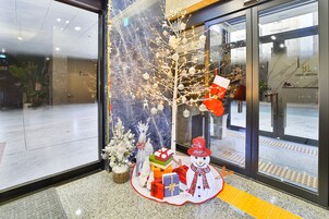 En festligt dekorerad entré med en julgran, presenter och en snögubbe.