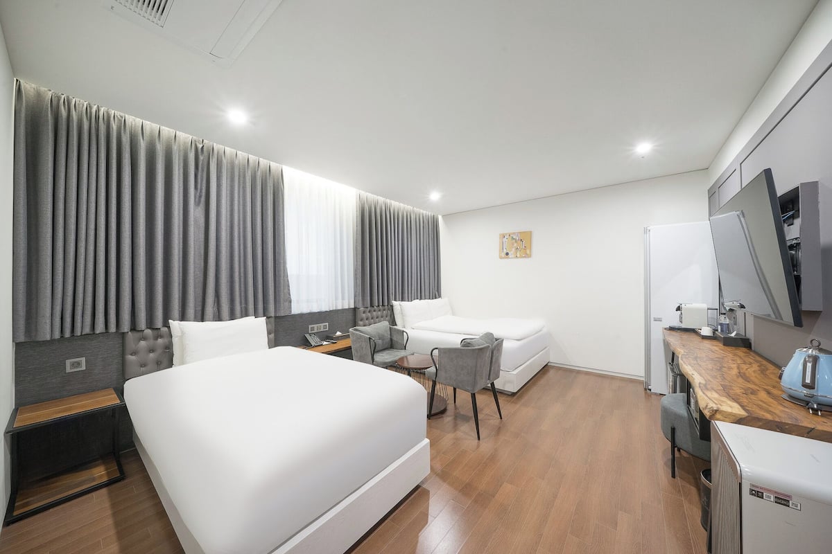 Una habitación de hotel moderna con una cama grande, un escritorio, una silla, una mesita y un televisor.