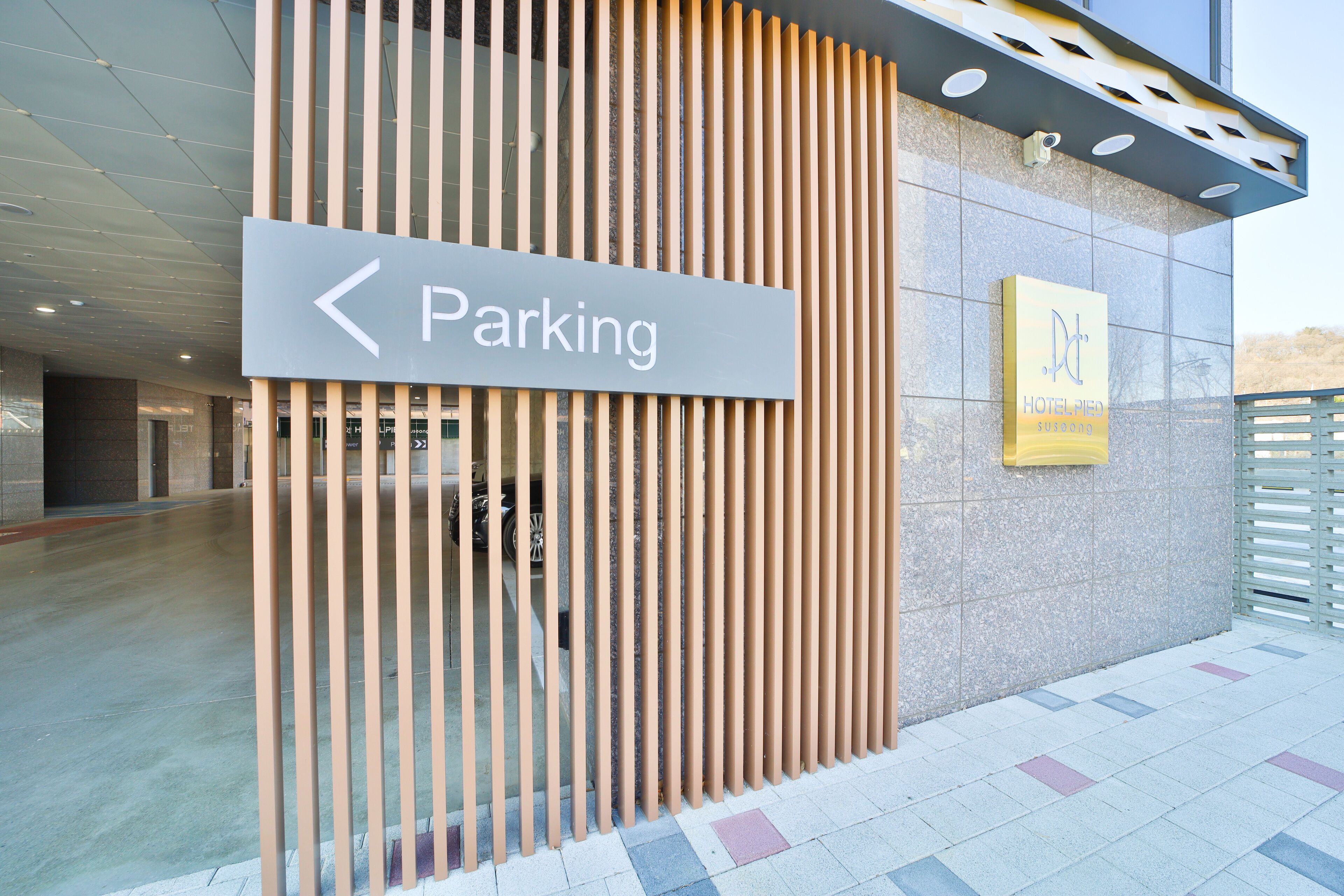 Entrada de un edificio con un cartel que indica un estacionamiento a la izquierda.