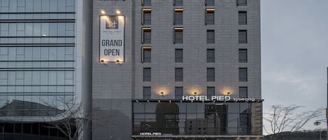 A modern hotel building with a sign indicating a grand opening.