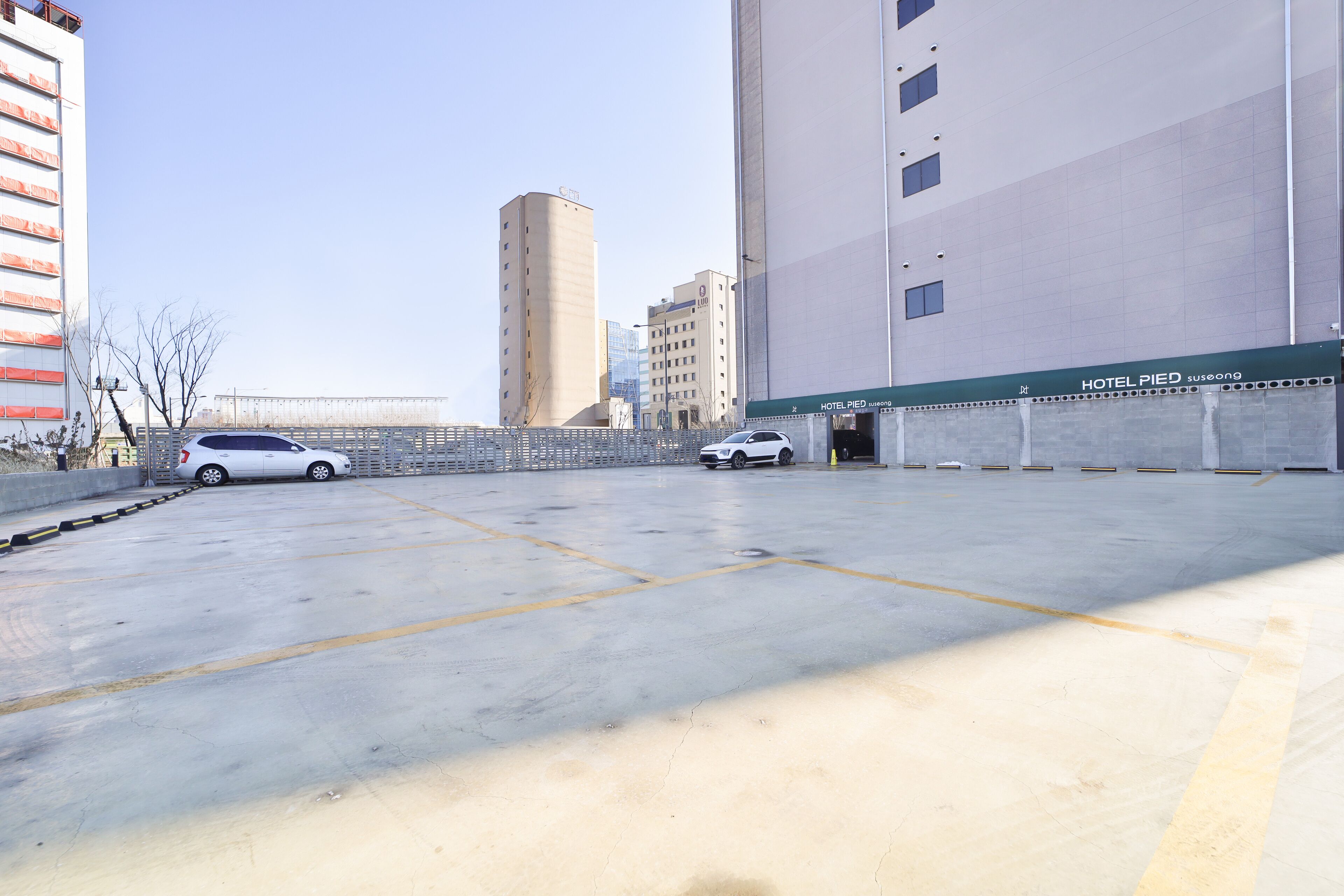 Een ruime, lege parkeerplaats met twee witte auto's.