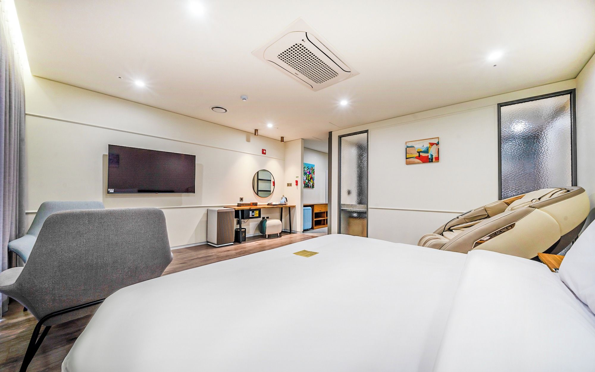 Une chambre d’hôtel équipée d’un lit, d’un bureau, d’une chaise, d’une télévision et d’une fenêtre avec du verre dépoli.