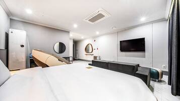 A modern hotel room with a large bed, a flat-screen TV mounted on the wall, a built-in heater, and a mirror.