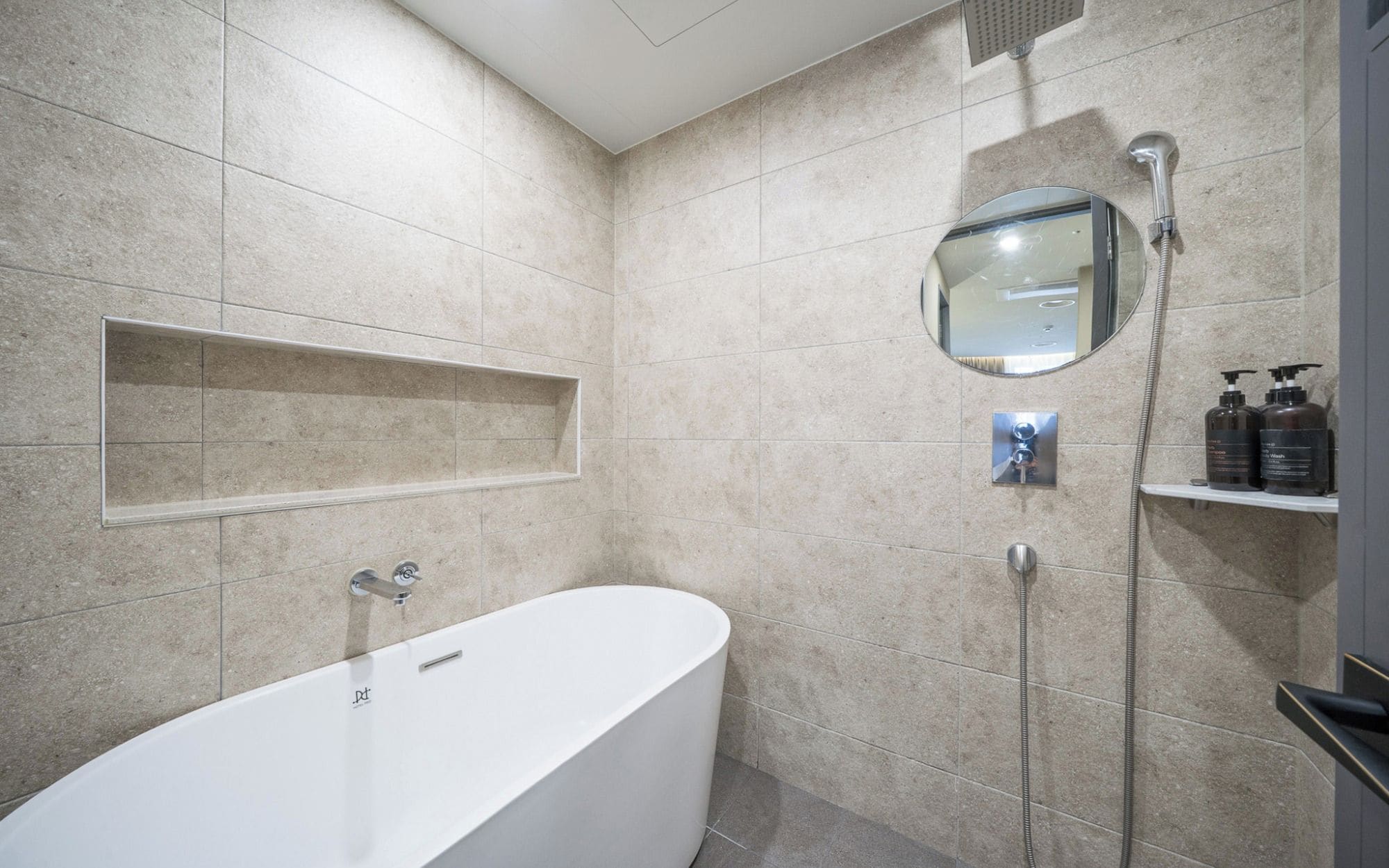 A modern bathroom with a freestanding bathtub, a wall-mounted mirror, and a showerhead.