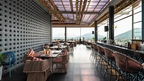A restaurant with a high ceiling, patterned wall, and a view of the mountains.