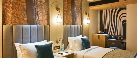 A hotel room with two beds, a desk, a mirror, and a zebra-patterned wall.