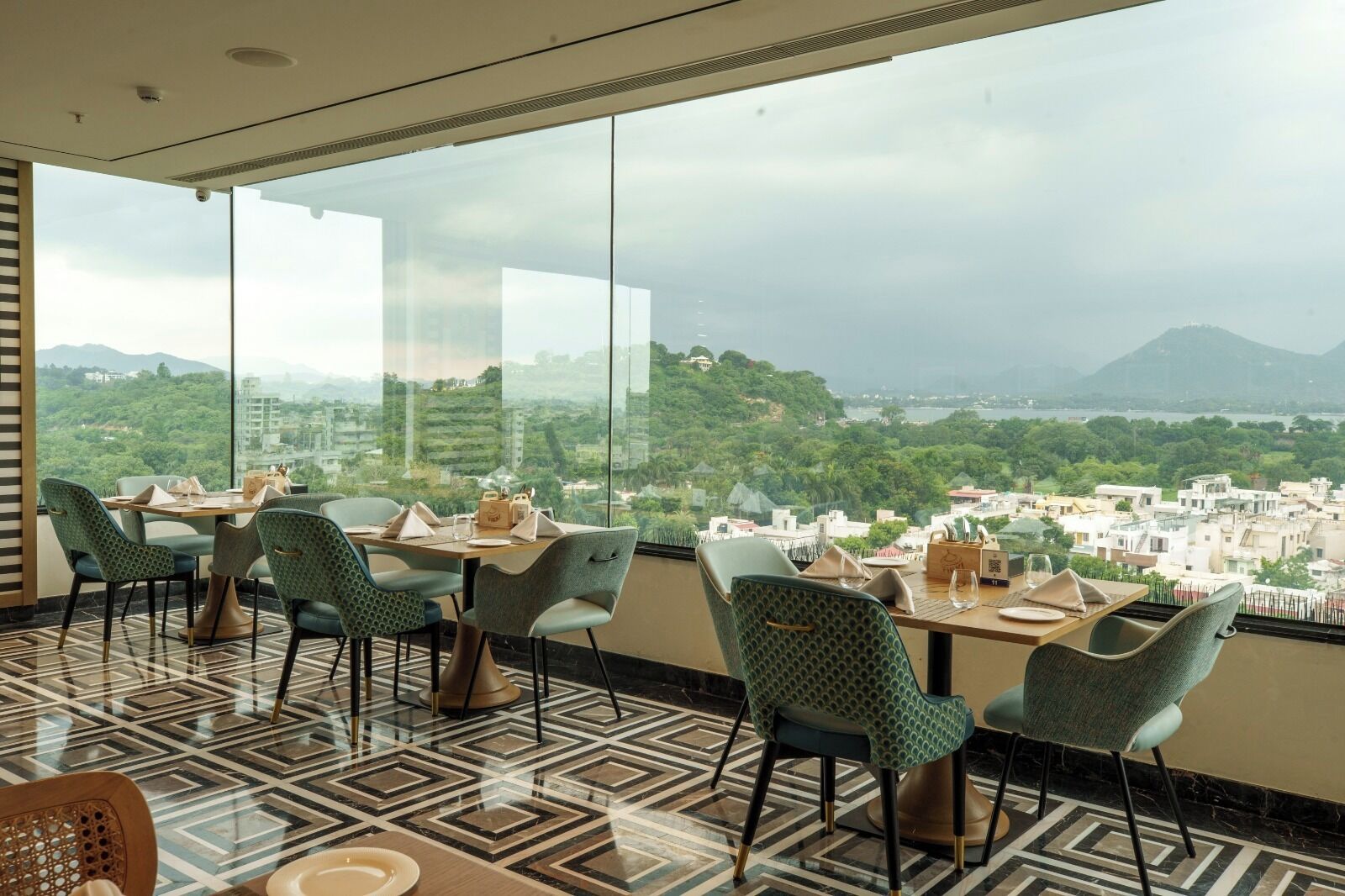 A restaurant with a panoramic view of a city and hills.