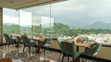 A restaurant with a panoramic view of a city and hills.