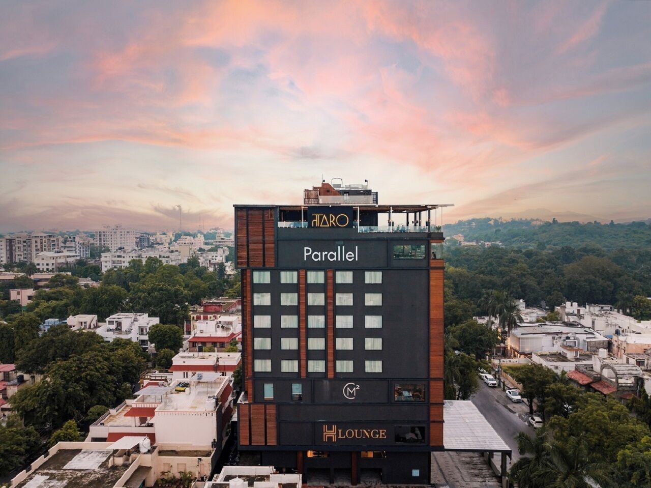 Un hotel llamado 'Parallel' con un área de lounge en la azotea, rodeado de un paisaje urbano.