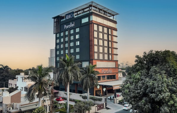 A tall building named 'Parallel' with a 'Starbucks' on the ground floor, surrounded by palm trees and other buildings.