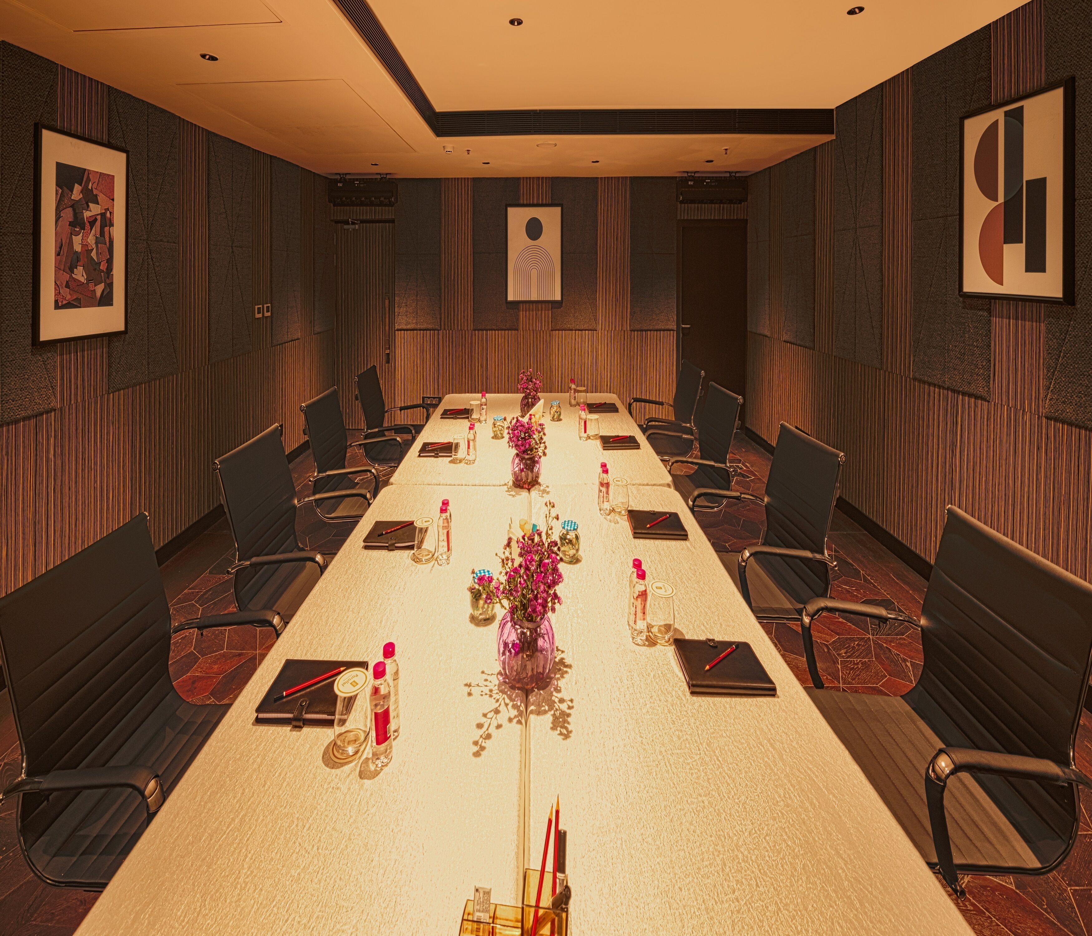 A conference room with a long table, chairs, and floral centerpieces.