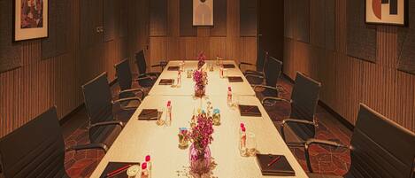 A conference room with a long table, chairs, and floral centerpieces.