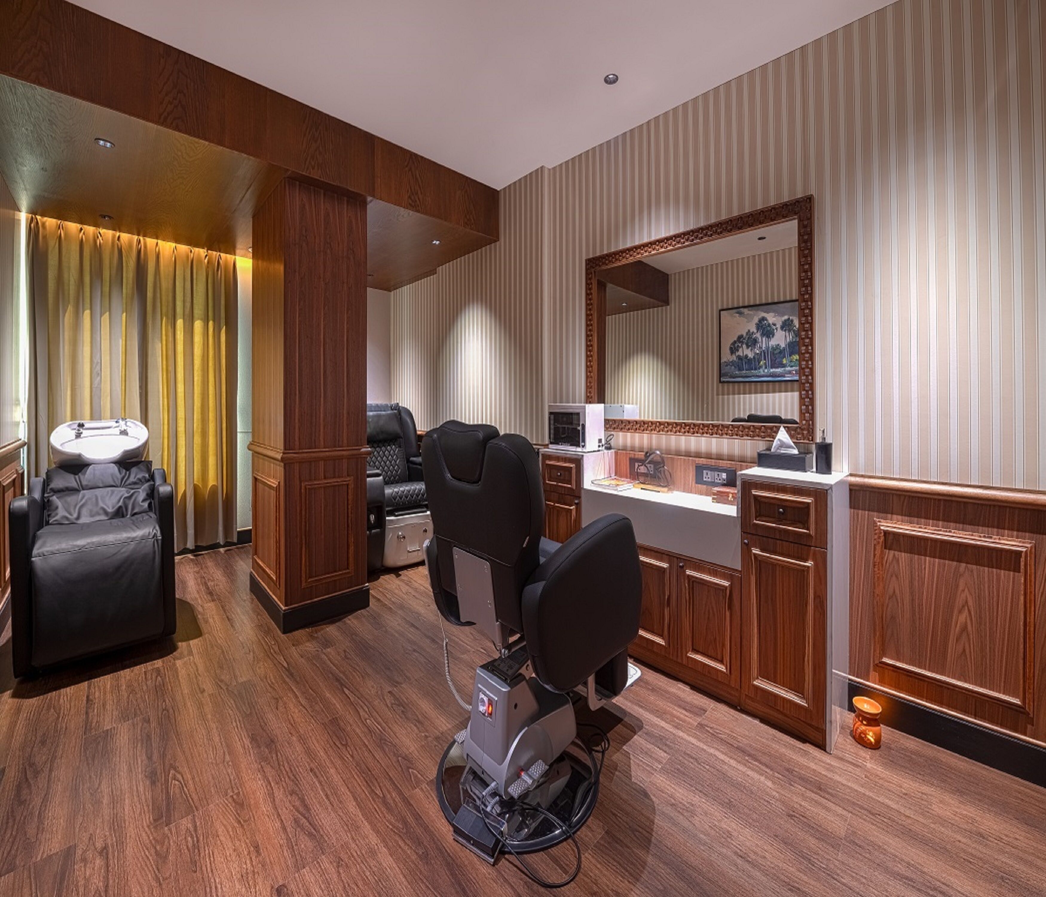 A room with a massage chair, a vanity with a mirror, and wooden paneling.