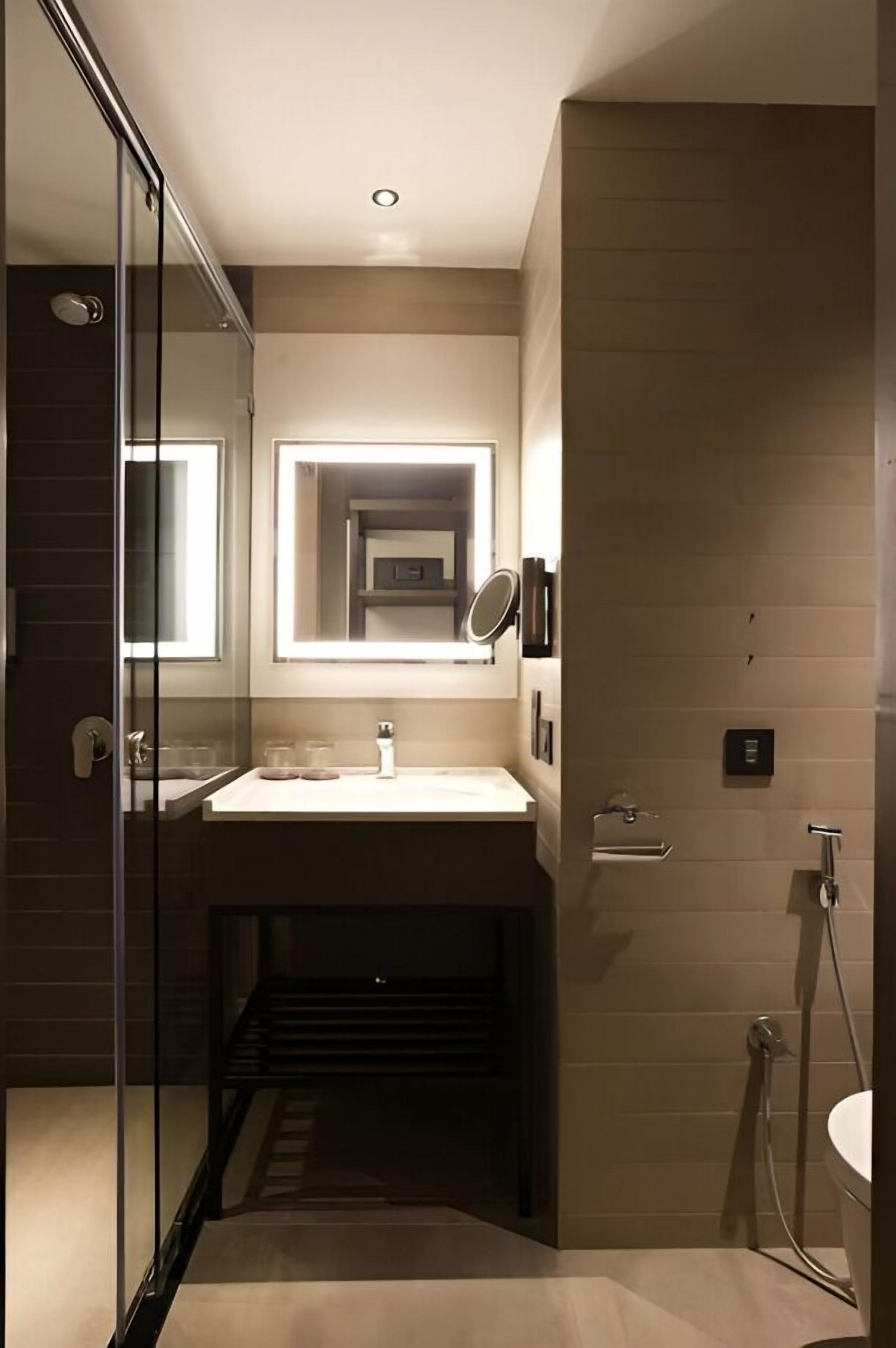 Un baño moderno con cabina de ducha de vidrio, lavabo integrado y espejo.
