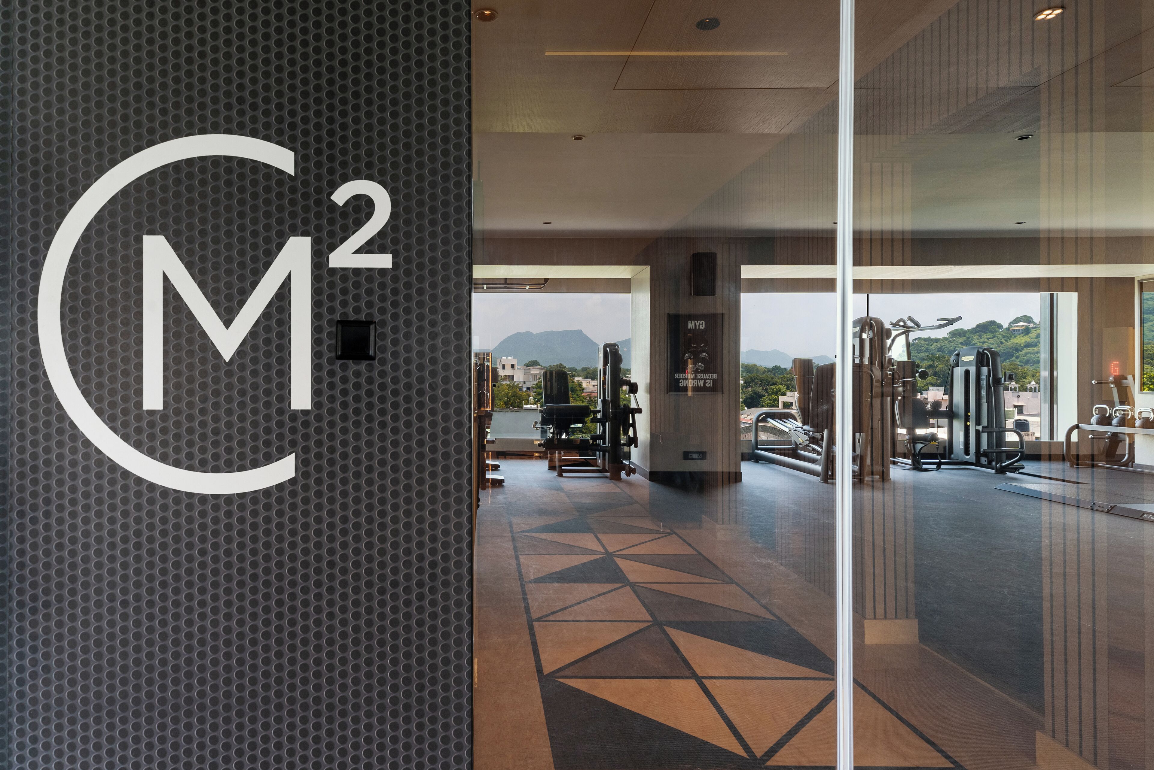 A gym area with exercise equipment and a view of mountains through large windows.