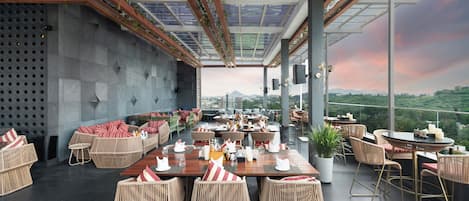 Un restaurante en la azotea con terraza, techo de vidrio y vistas a la ciudad.