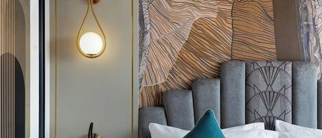 A modern hotel room with a large bed, a bedside table with a lamp, and a wall with a textured pattern.
