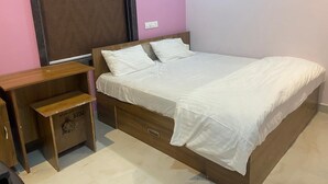 A bedroom with a wooden bed, a nightstand, and a small wooden cabinet. - Hotel Bablu Yadav (Maheshwaram)