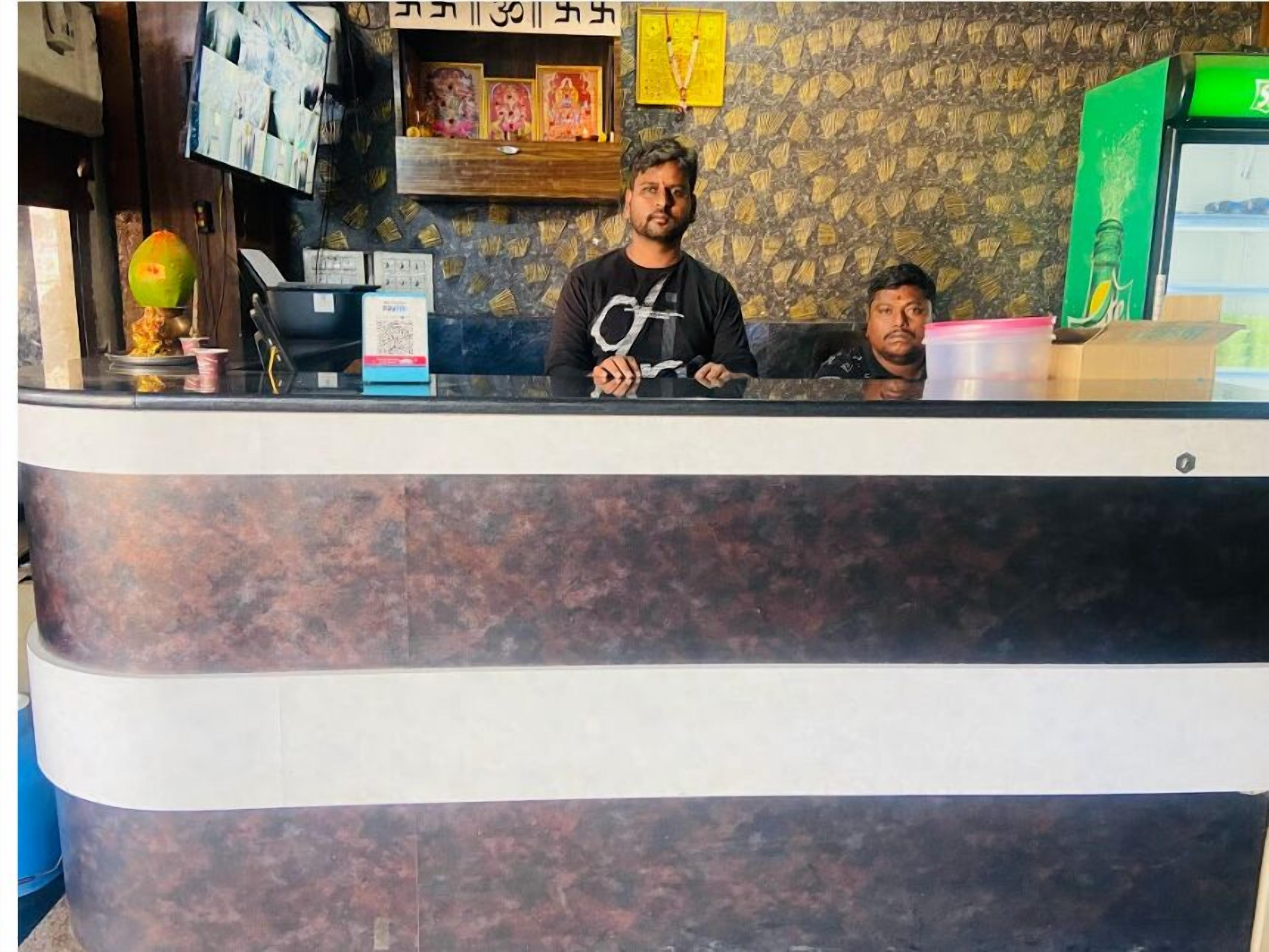 A reception desk with a patterned wall, a green vending machine, and a small shrine with framed pictures.
