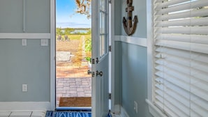 A door leading to a patio with a view of a grassy area and a body of water. - Large WATERFRONT River House, Boater's Paradise! Brand New Dock, Walk to Beach, 1 mile to Boat Ramp (Saint Augustine)