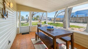 A covered patio with a wooden table and bench, large windows, and a view of a residential area. - Large WATERFRONT River House, Boater's Paradise! Brand New Dock, Walk to Beach, 1 mile to Boat Ramp (Saint Augustine)