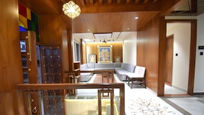 A modern interior with a wooden staircase, a seating area with a sofa and chairs, and a decorative floor pattern. - The Sky Imperial Hotel Sugam (Nathdwara)