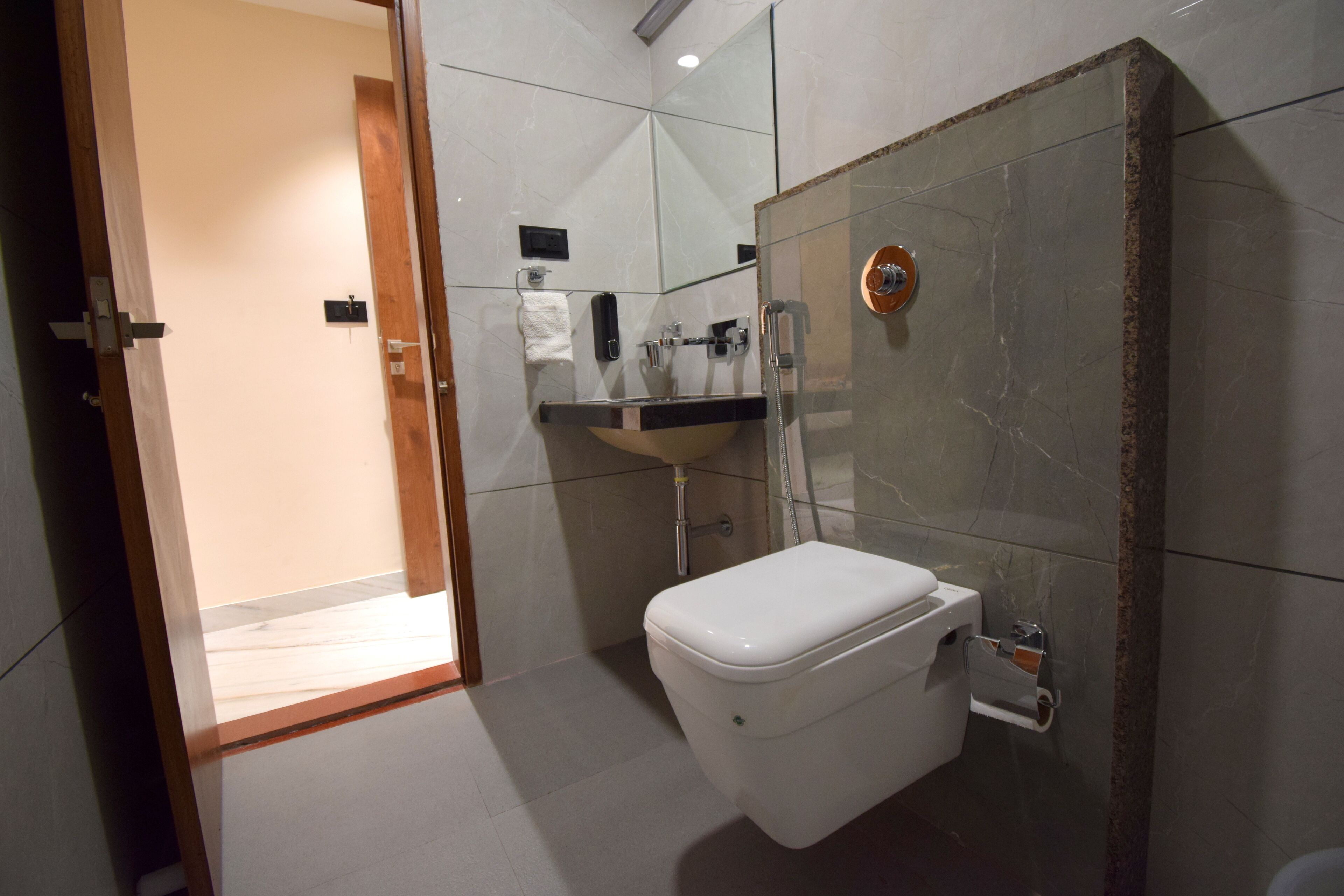A modern bathroom with a glass-enclosed shower, a white toilet, and a marble-tiled sink area.