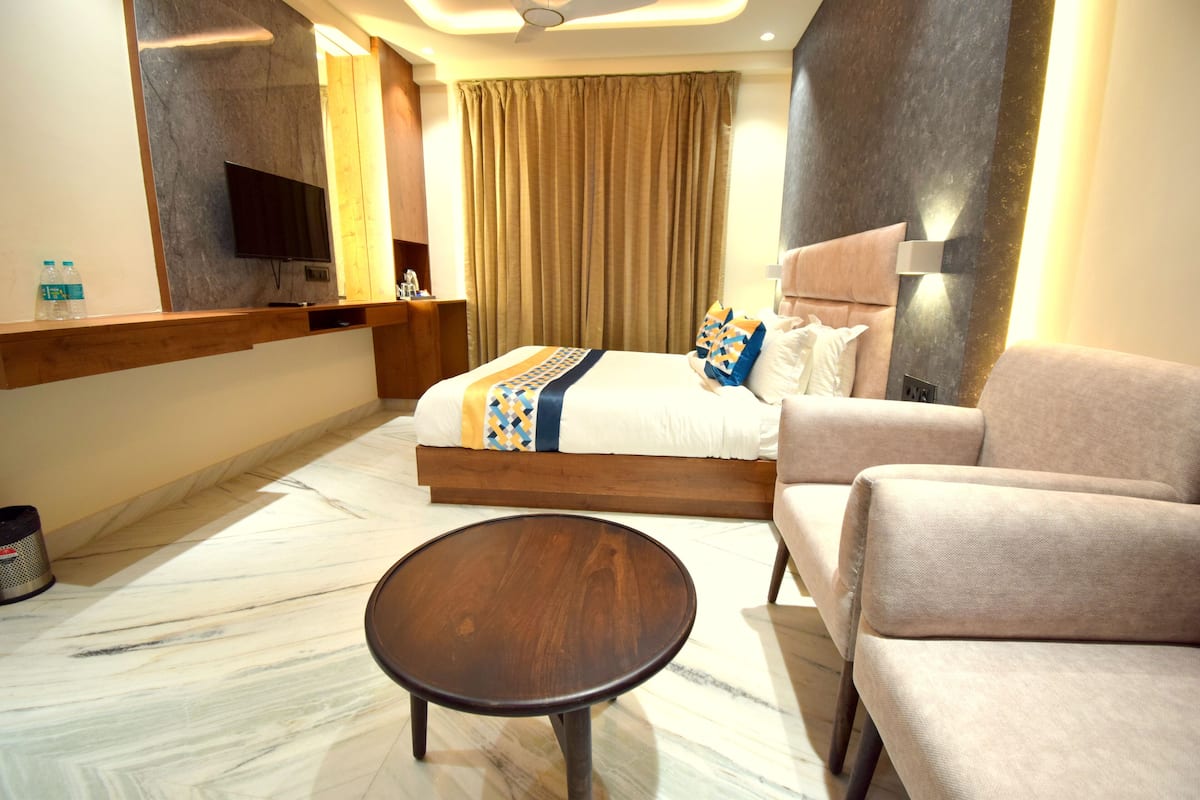 Une chambre d’hôtel comprenant un lit, un canapé, une table basse, une télévision et une salle de bain.