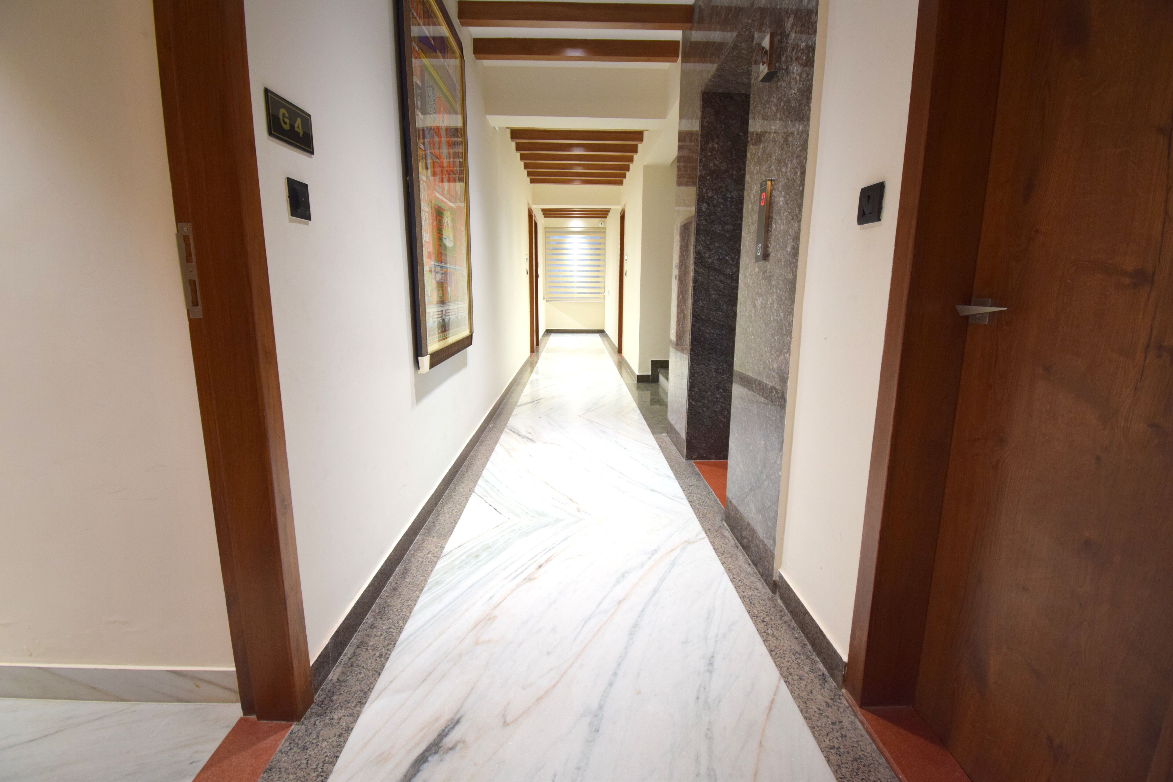 Un corridoio con pavimento in marmo, stipiti delle porte in legno e soffitto a travi in legno.