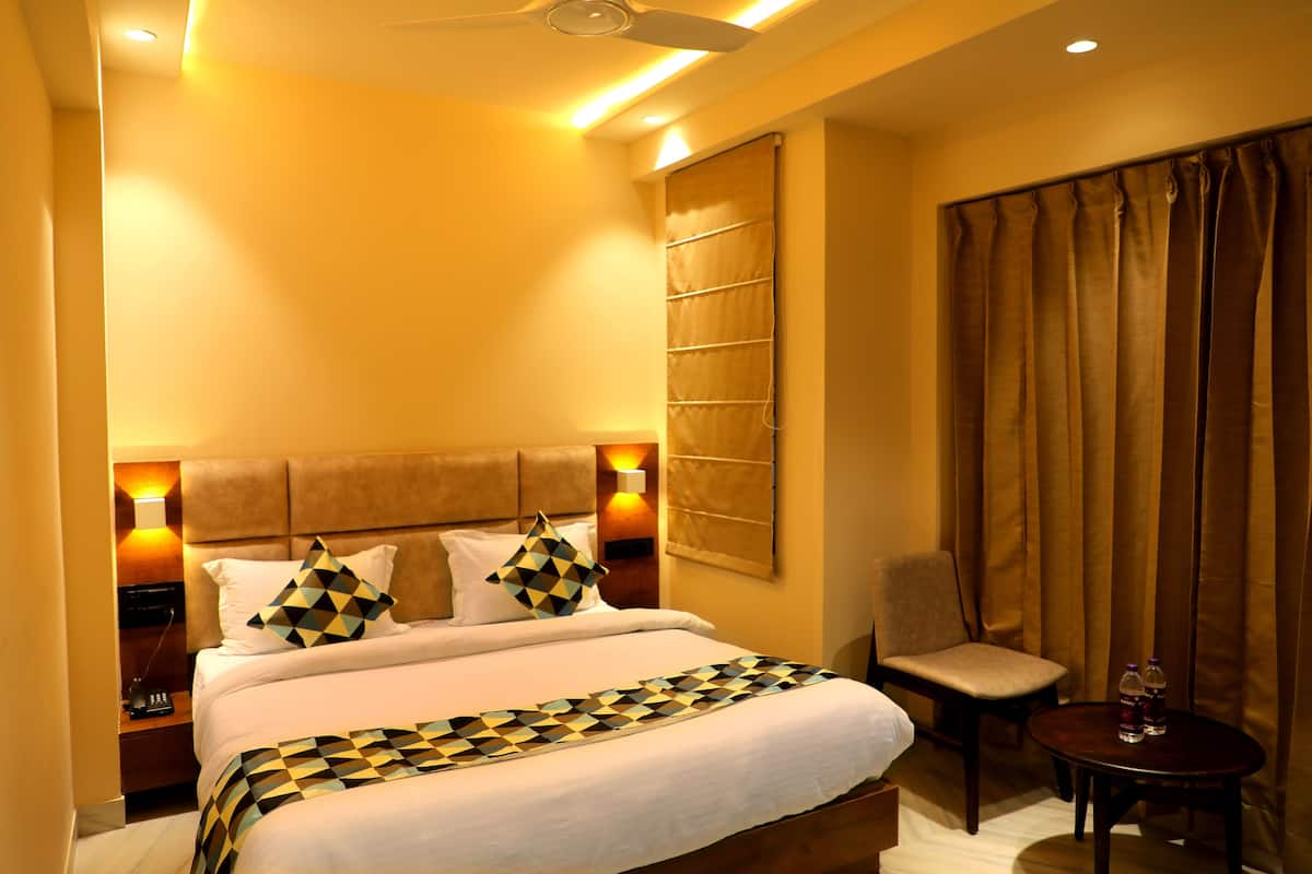 Une chambre d’hôtel avec un lit, une chaise, une petite table et un rideau.