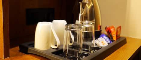 Un plateau avec une cafetière, deux tasses blanches, un verre et quelques en-cas.