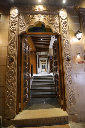Een sierlijke hotelentree met een brede, statige trap naar een receptie.