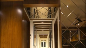 A hallway with a decorative floor pattern, wooden walls, and a metal railing. - The Sky Imperial Hotel Sugam (Nathdwara)
