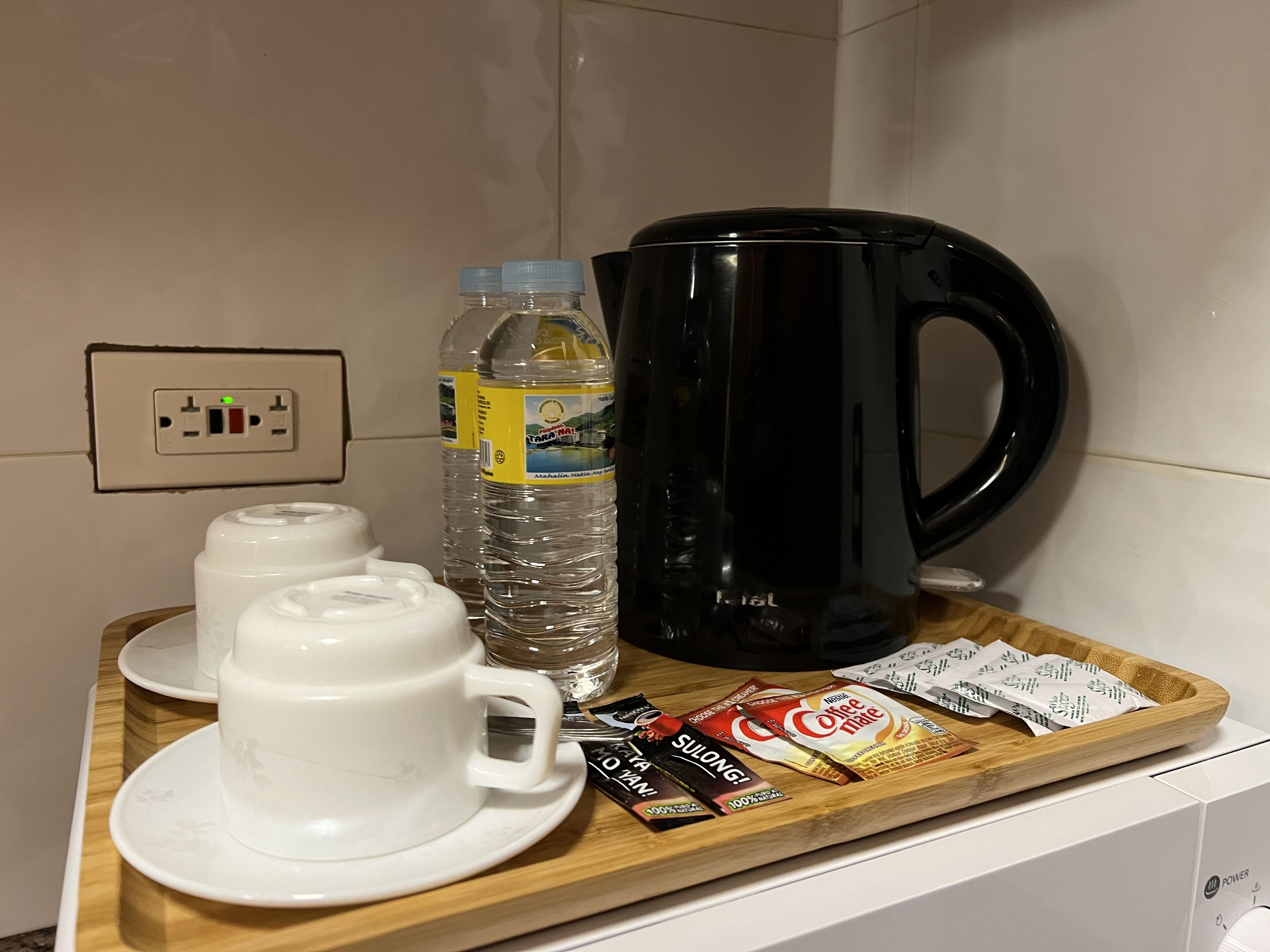Una encimera de cocina con una cafetera, botellas de agua y cápsulas de café.
