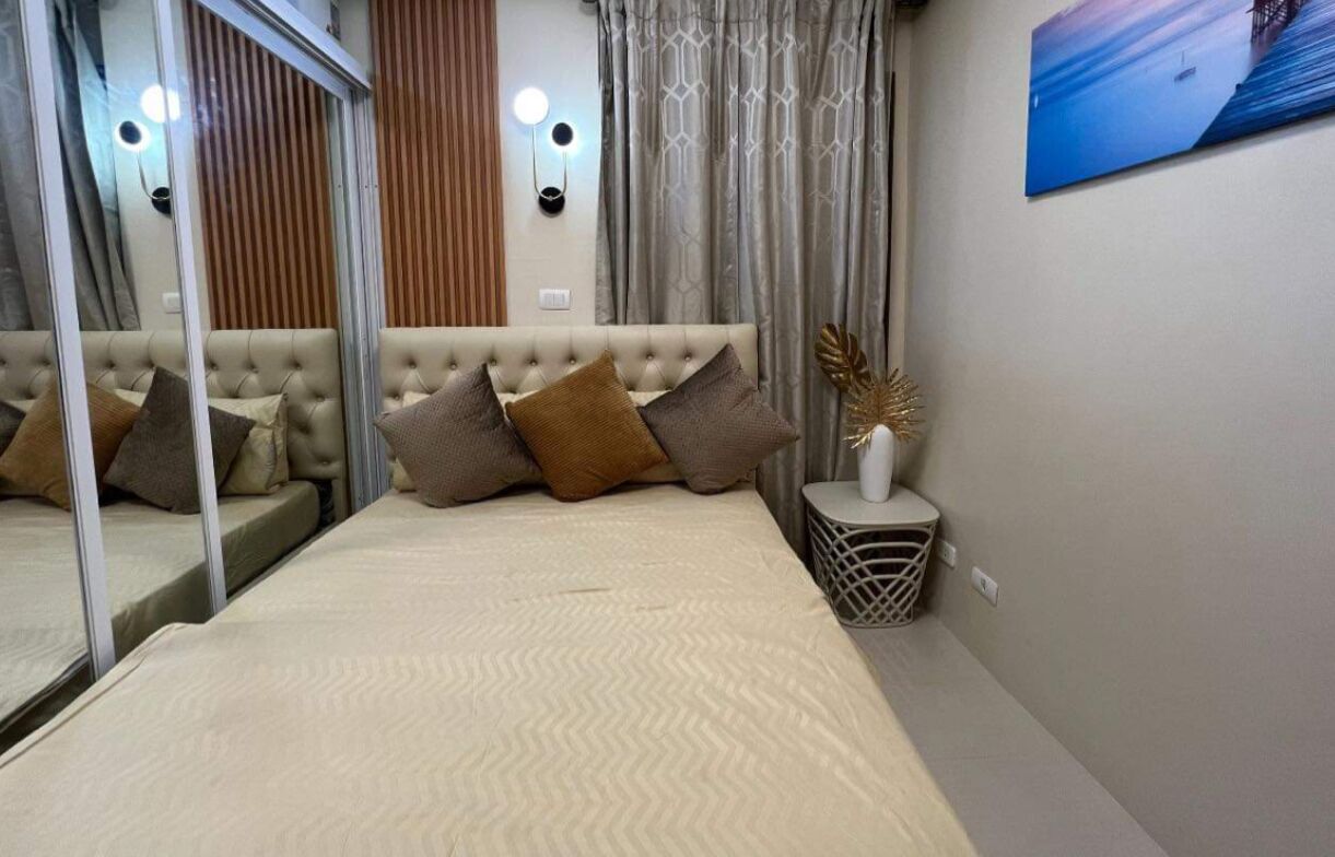 Una camera da letto con un letto grande, uno specchio, una lampada a parete e un quadro.
