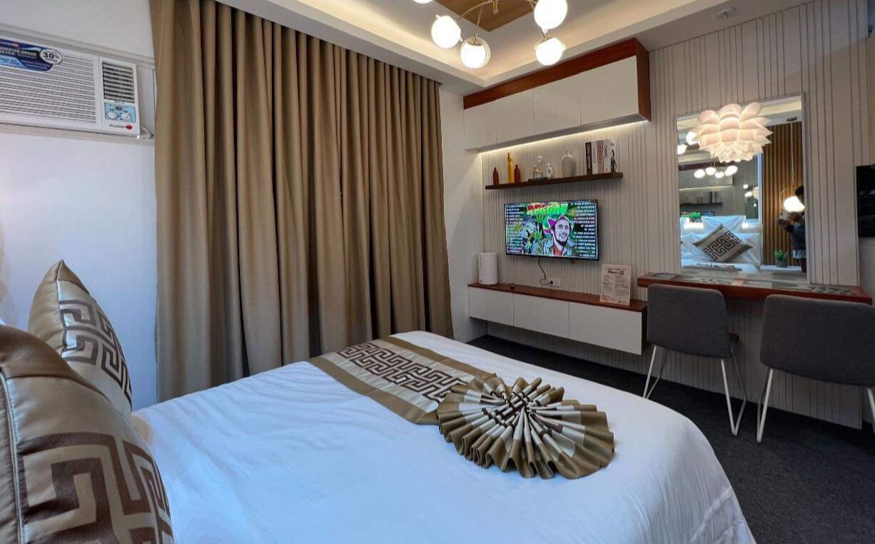 Une chambre d’hôtel avec un lit, un bureau, une télévision et une fenêtre avec des rideaux.