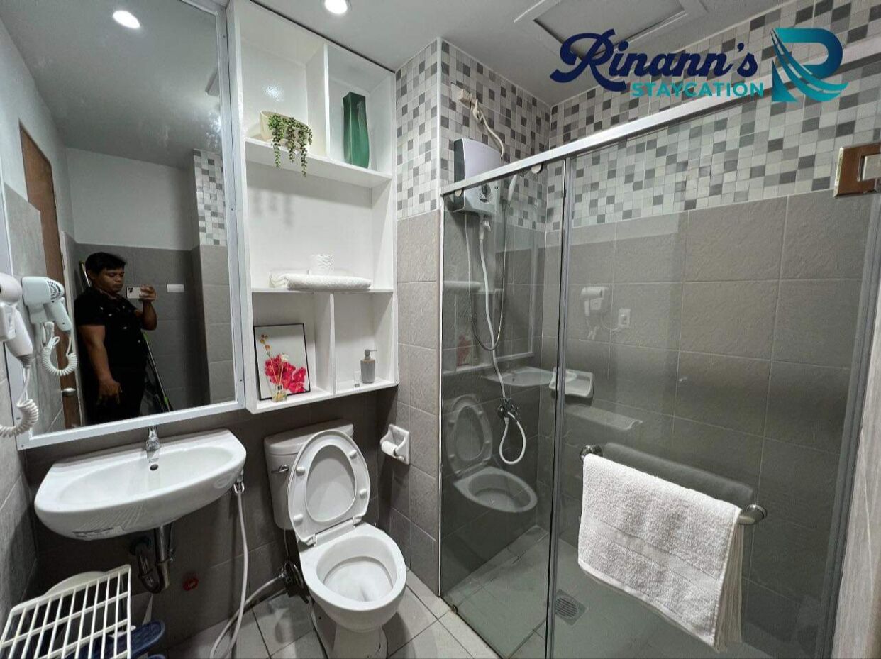 A modern bathroom with a glass-enclosed shower, a white sink, and a toilet.