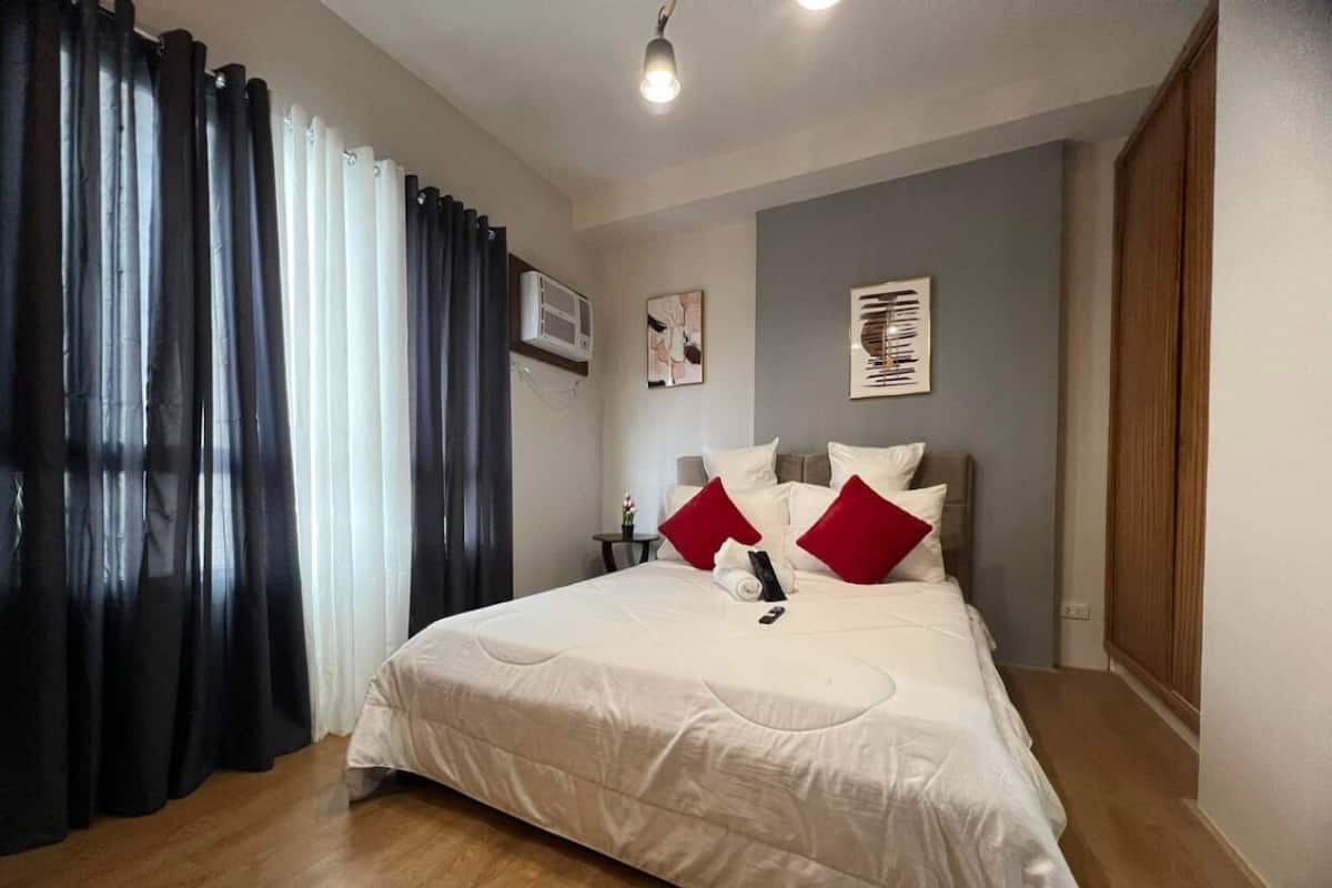 A neatly arranged bedroom with a bed, curtains, and a ceiling light.