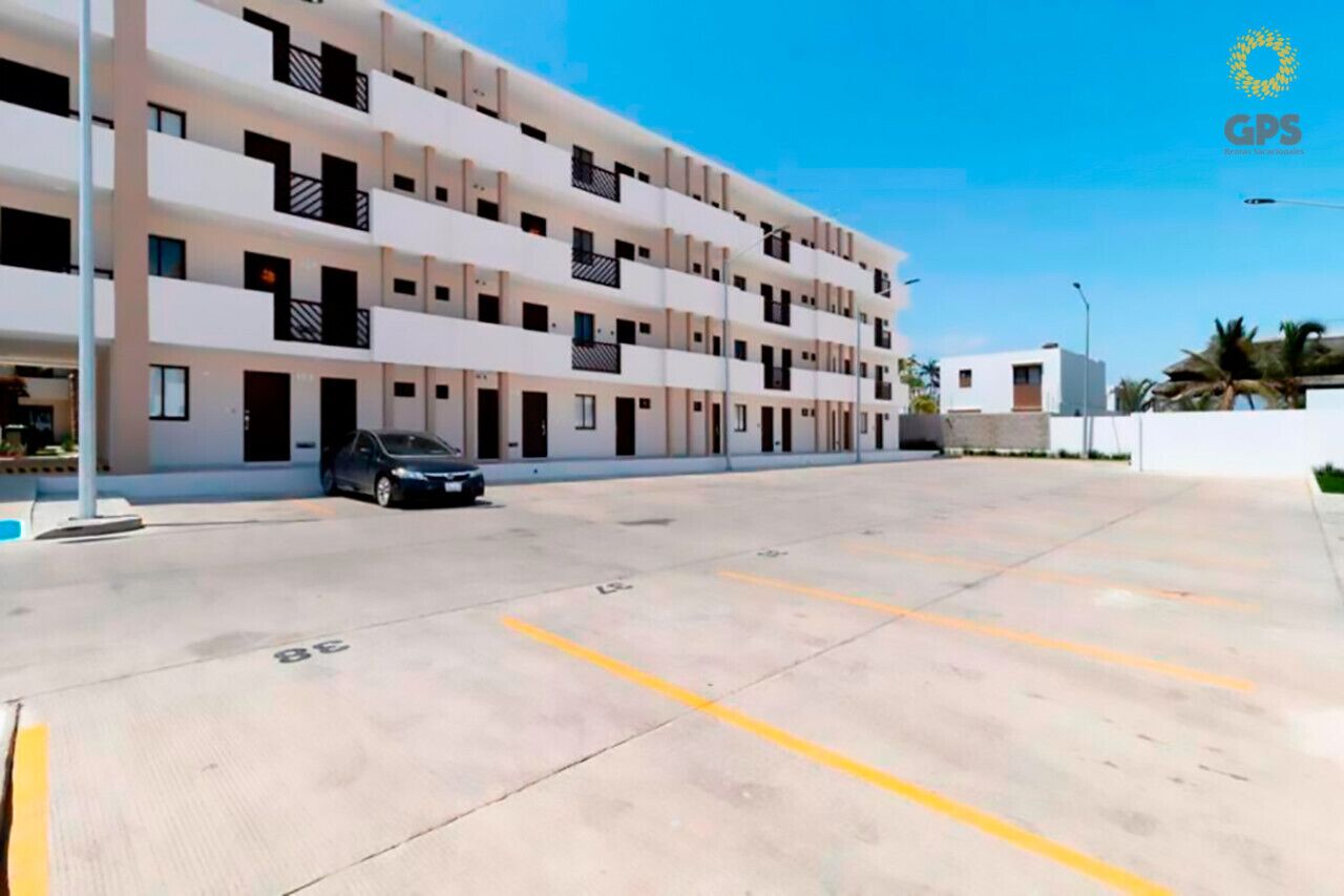 A multi-story building with a parking lot in front.