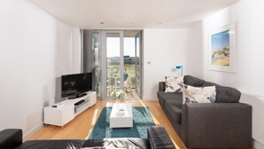 A modern living room with a flat-screen TV, a grey sofa, and a coffee table.