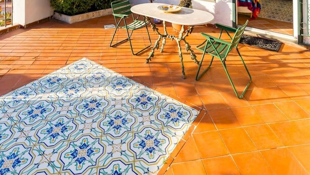 Una terraza en la azotea con suelo de baldosas, una mesa con sillas y una planta en maceta.