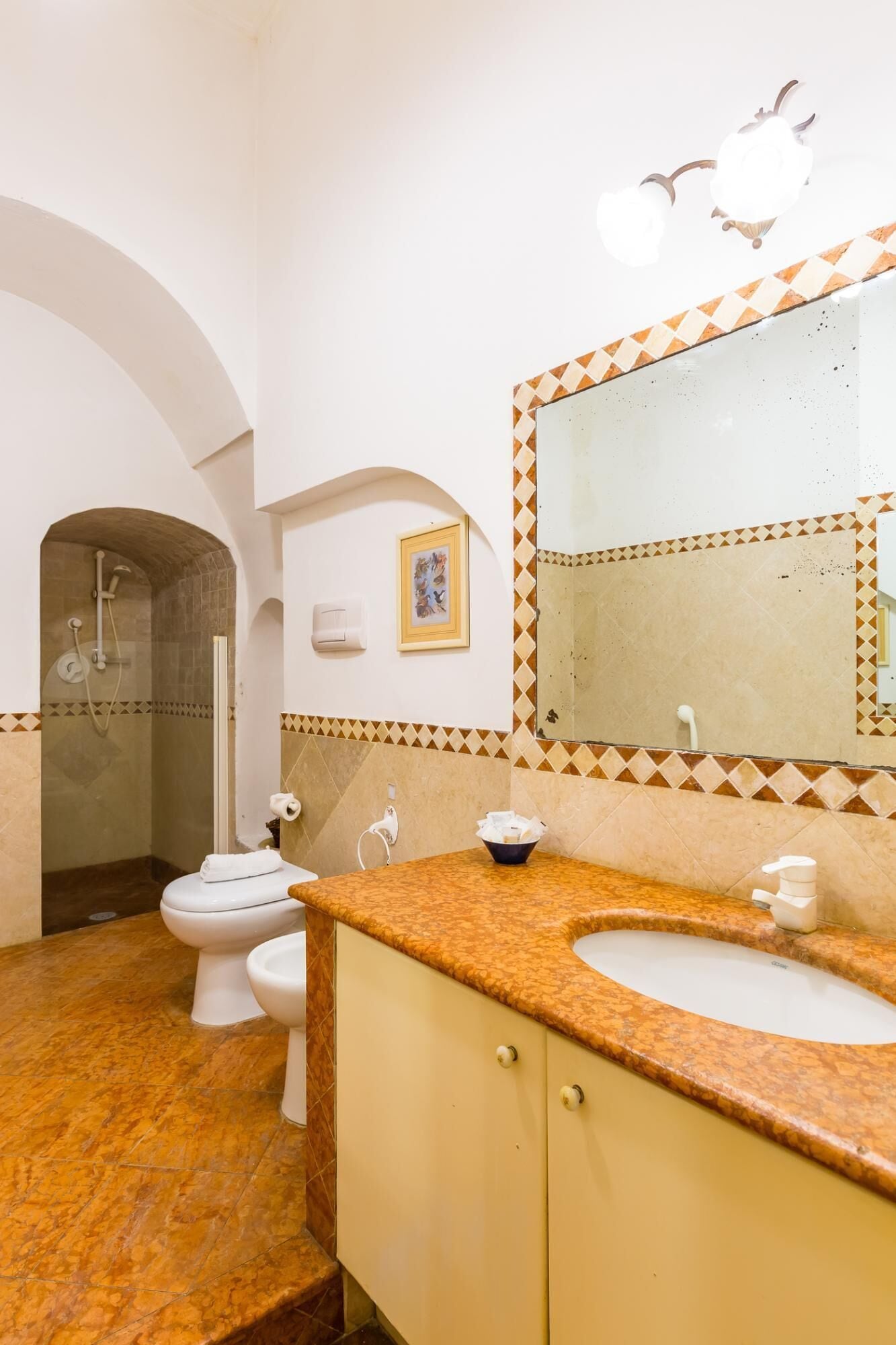 Une salle de bain avec une douche, deux toilettes, un lavabo et un miroir.