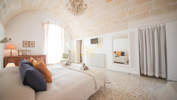 A bedroom with a large bed, a chandelier, a mirror, and a radiator. - TD Casa Altomare w Terrace Over Historic Center (Monopoli)